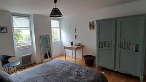 A bedroom with a bed, a chair, a desk, a mirror, and a wardrobe. - Gîte "La P'tite Jeannette", between land and sea, on the banks of the Charente. (Saint-Savinien)