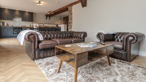 A modern living room with a leather sectional sofa, a wooden coffee table, and a herringbone-patterned rug. - Betsy's Burrow (Bridlington)