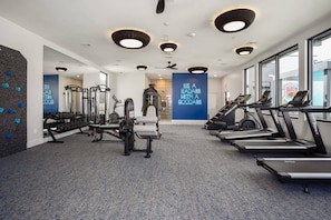 Une salle de sport moderne équipée de tapis de course, de machines de musculation et d’un mur d’inspiration.