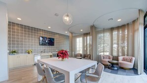 A modern kitchen with a white countertop, grey chairs, and a large dining table.