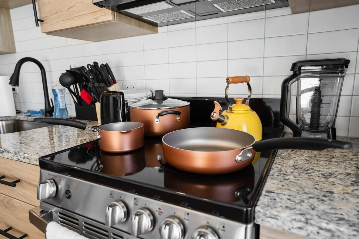 A kitchen with a stove, pots, a kettle, and a coffee maker.