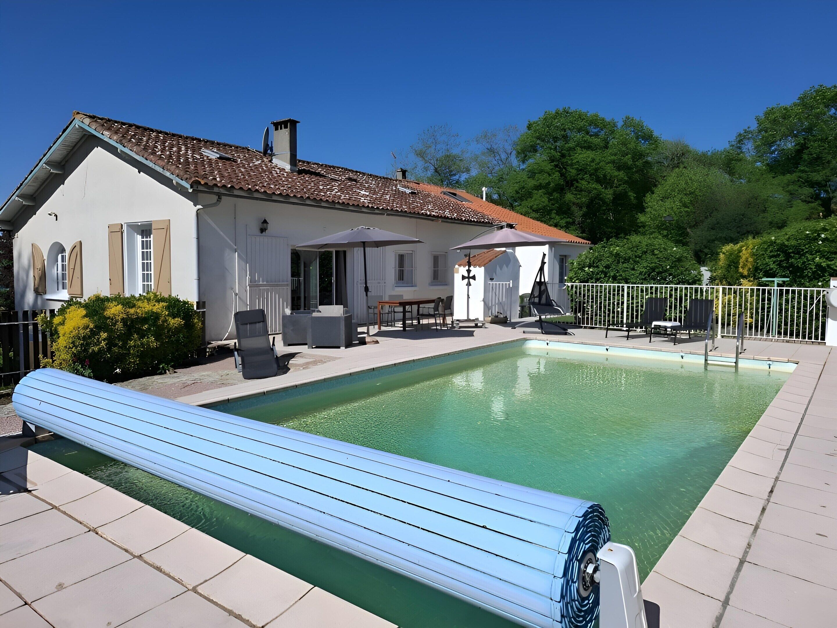 Une maison avec une piscine, du mobilier d’extérieur et une terrasse clôturée.