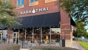 Un edificio de ladrillo con un letrero que dice "NARA THAI" y un área de estar al aire libre cubierta.