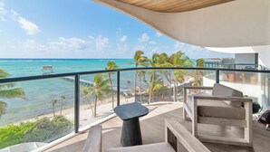 A modern balcony with a view of the ocean and palm trees. - Charming 2-bedroom apartment in lovely Dreams Tulum (Dreams Tulum)