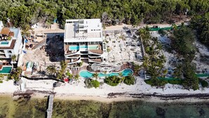 An aerial view of a resort with a large building, multiple swimming pools, and a pier extending into the water. - Charming 2-bedroom apartment in lovely Dreams Tulum (Dreams Tulum)