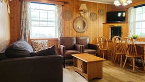 Una sala de estar acogedora con sofá, sillón, mesa de centro de madera y un comedor con sillas de madera y una pequeña mesa.