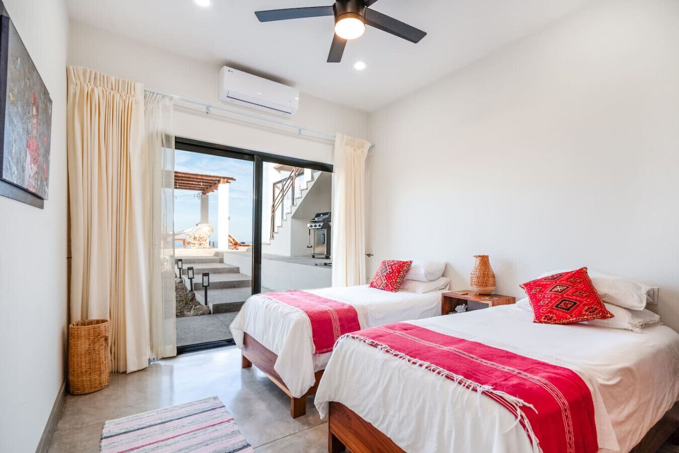 A hotel room with two beds, a ceiling fan, an air conditioning unit, and a view of the outside.