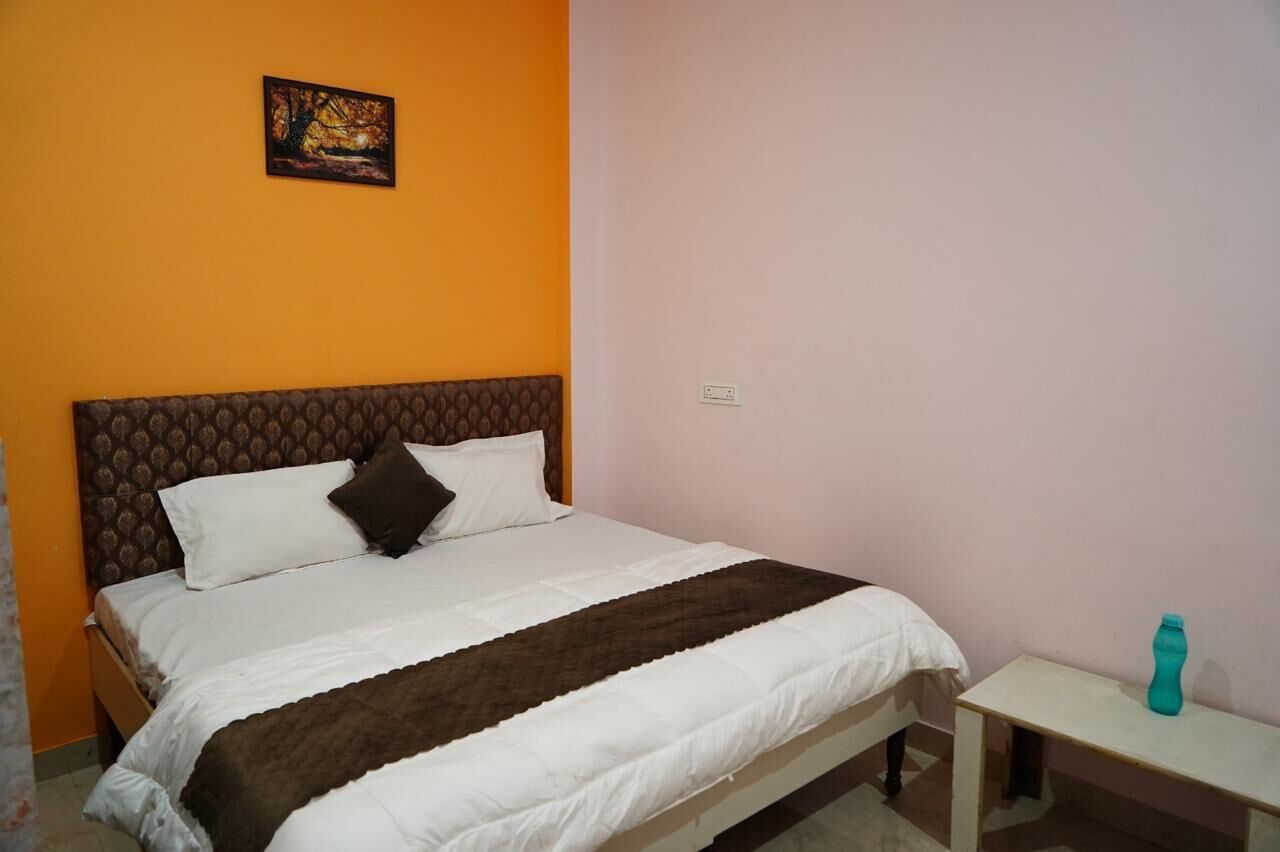 A bed with a patterned headboard, a bedside table, and a picture on the wall.