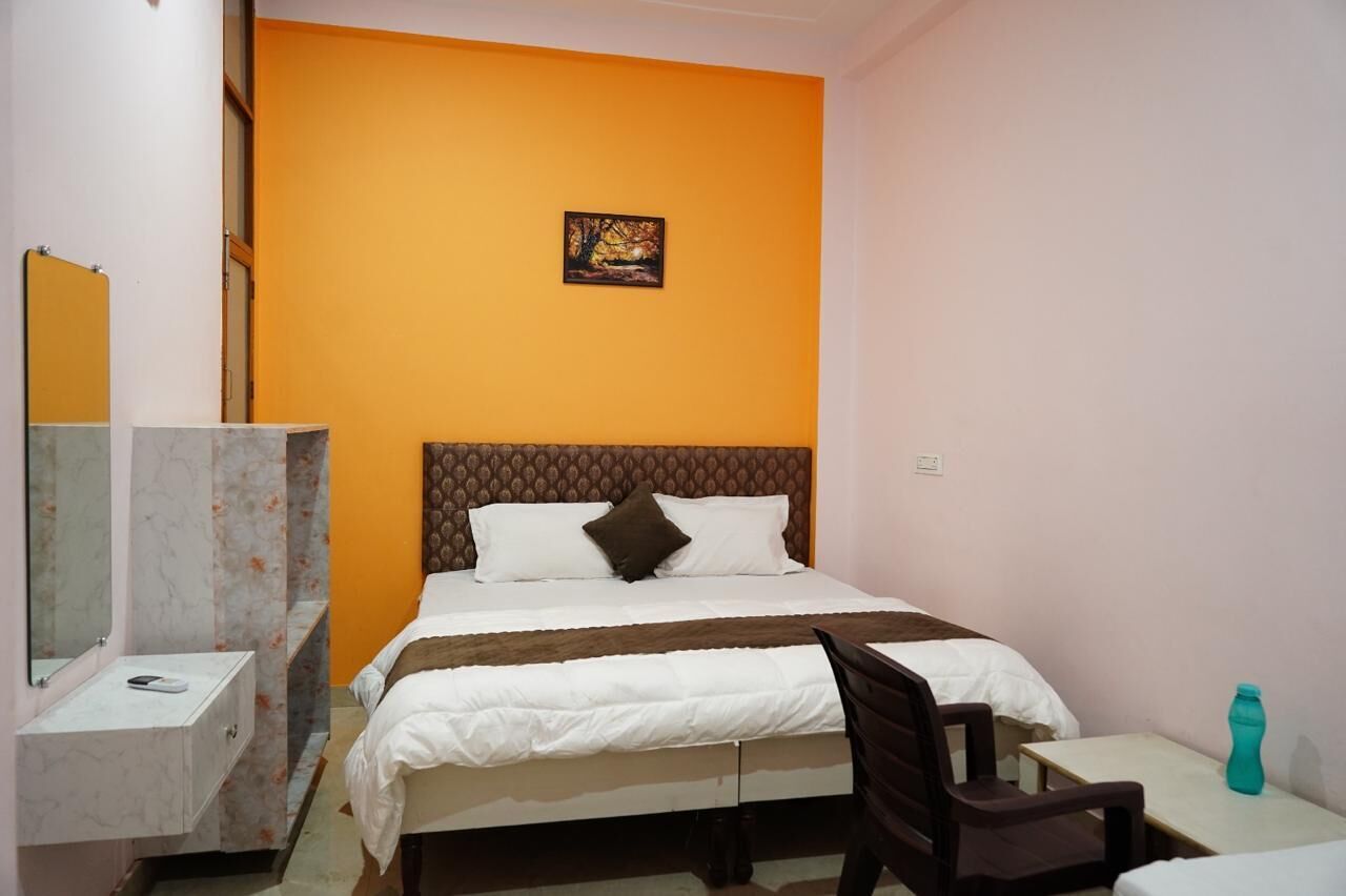 Un dormitorio con cama, escritorio, silla y una mesita.