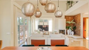 A spacious living area with a wooden dining table, a large flat-screen TV, and a cozy seating arrangement. - Villa Oriente - Family Villa with pool in Marbella East (Marbella)