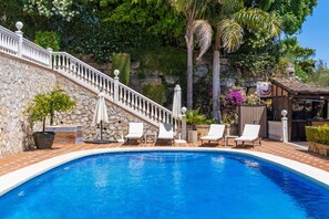A swimming pool with a stone wall and a white balustrade.