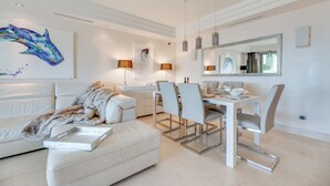 Un salon moderne avec un canapé blanc, une table à manger et des chaises, ainsi qu’un grand miroir.
