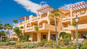A multi-story hotel with balconies, palm trees, and a clear blue sky. - Penthouse 2BR with Sea Views & Heated Pool (Benahavís)