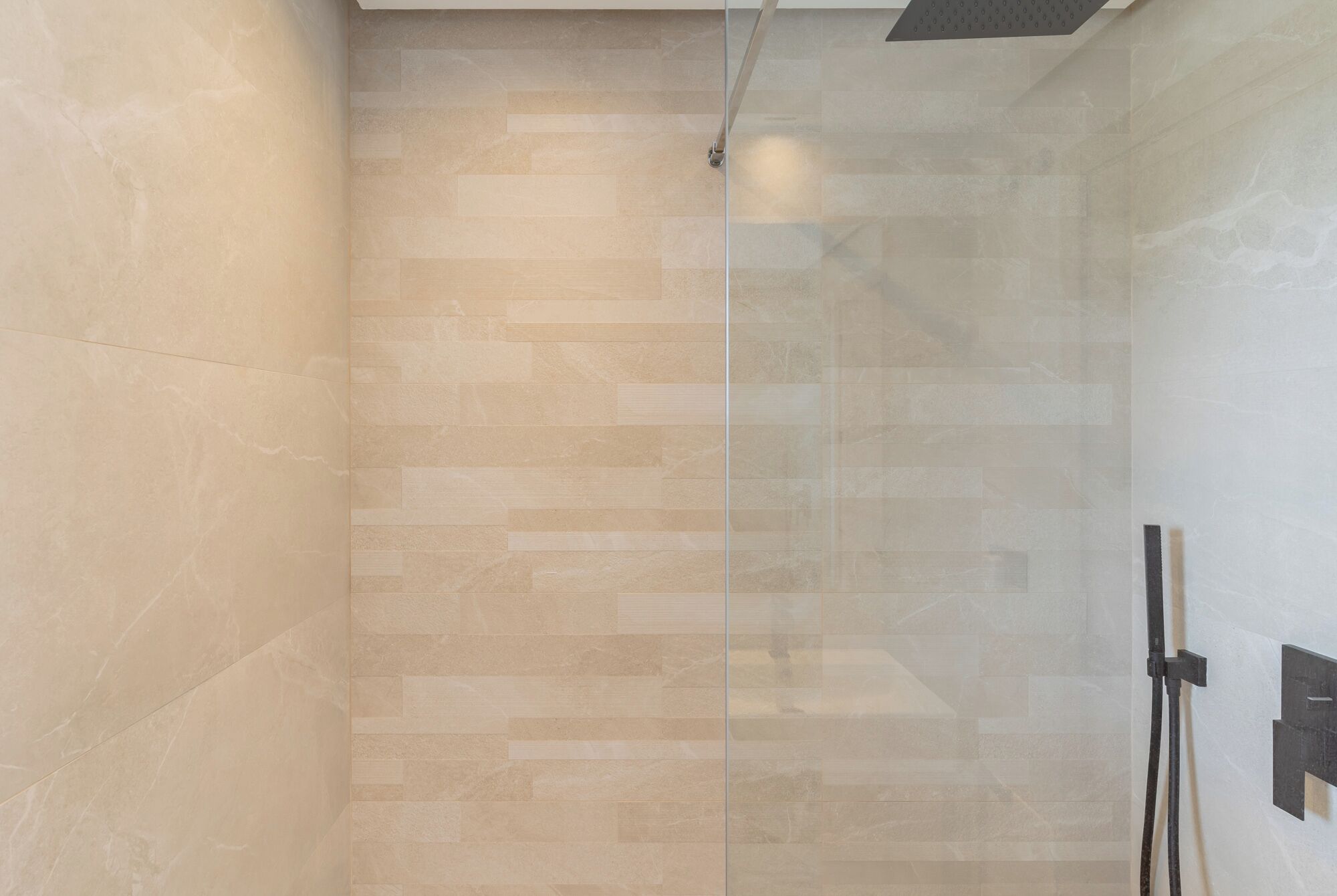 Una ducha moderna con puerta de cristal y pared de azulejos.