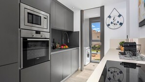 Eine moderne Küche mit integrierten Geräten, ein Essbereich mit Glastisch und Blick ins Freie.