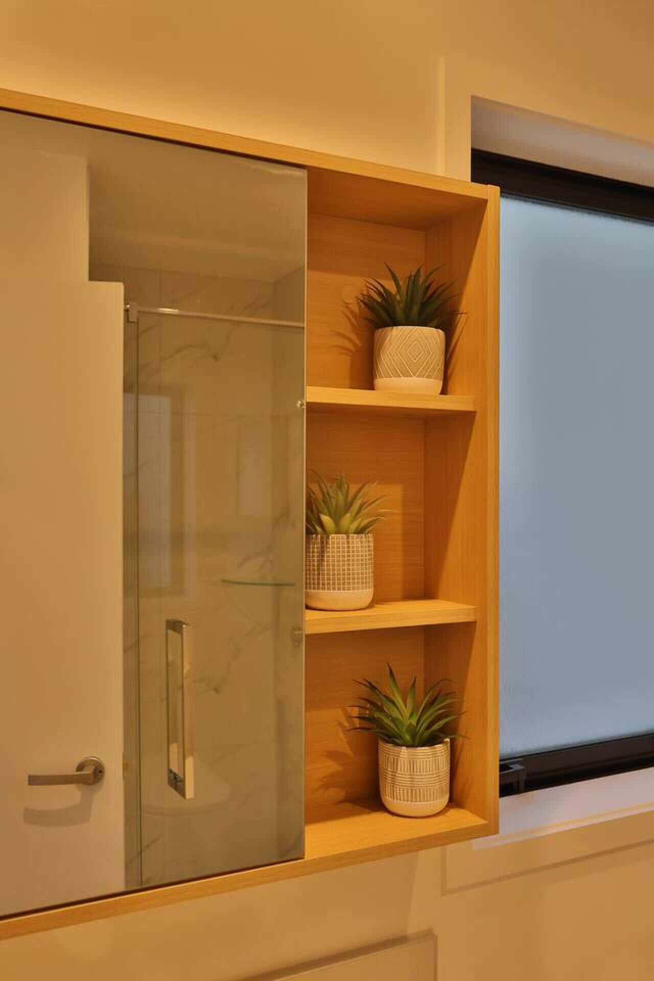 Een kamer met een glazen deur, houten planken en potplanten.