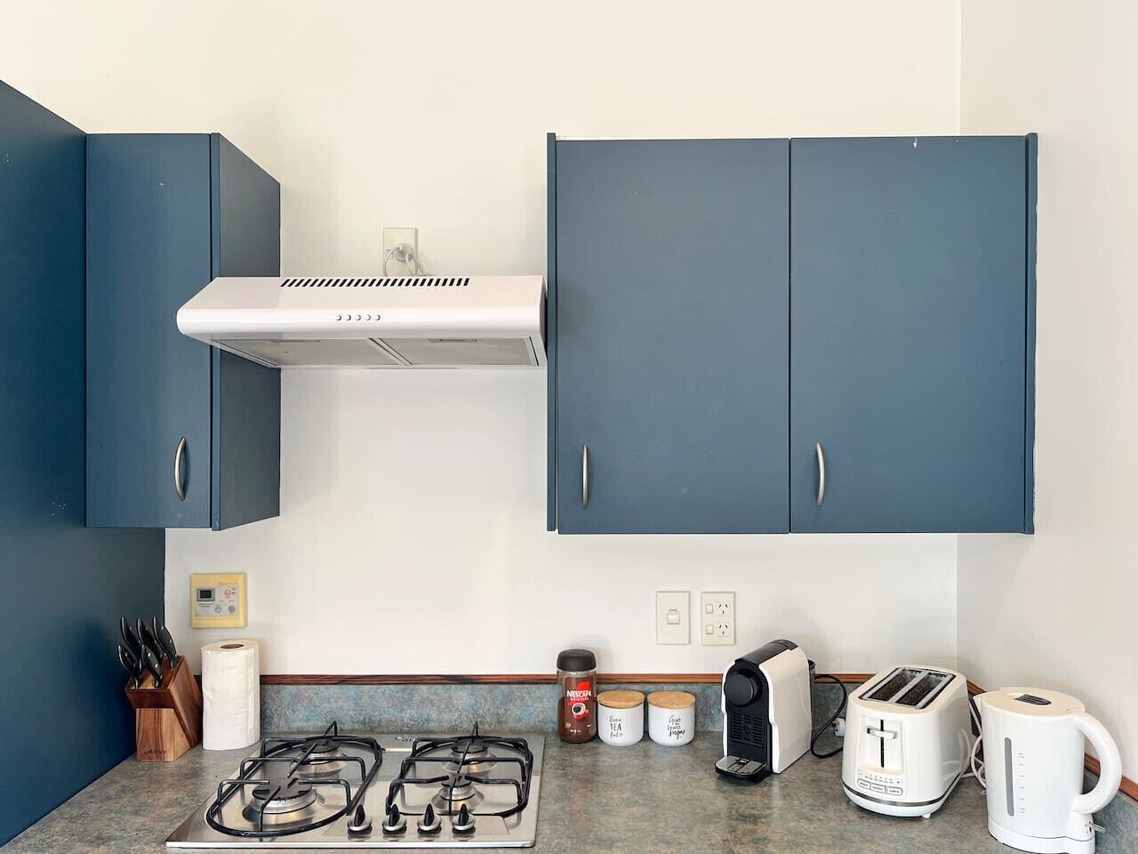 Eine kleine Küche mit Gasherd, Toaster, Wasserkocher und Schränken.