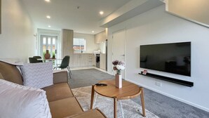 A modern living room with a sofa, a coffee table, and a TV. - Homey and Bright Riccarton 1BR (Christchurch)