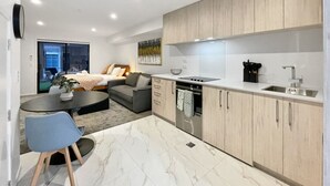 Une cuisine moderne avec des meubles en bois, un plan de travail en marbre et un coin repas comprenant une table et des chaises.