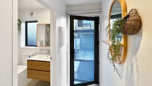 Une salle de bain moderne avec un meuble-lavabo en bois, un grand miroir et une plante suspendue.