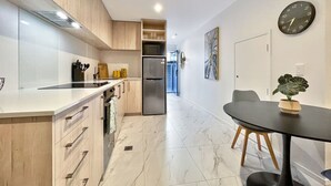 Une cuisine moderne avec des meubles en bois, un réfrigérateur en acier inoxydable et un sol en marbre.