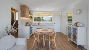 Une cuisine moderne avec un coin repas, des meubles en bois et une vue sur la verdure environnante.
