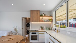 Une cuisine compacte équipée d’un four encastré, d’un évier et d’une fenêtre donnant sur un quartier résidentiel.
