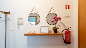 A wall-mounted shelf with a framed document, a potted plant, and a fire extinguisher.