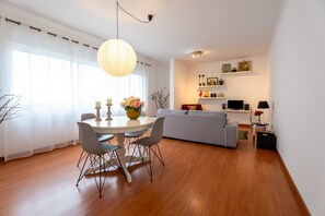 Un salon moderne comprenant un coin repas, un canapé gris, un téléviseur et une étagÚre décorative.