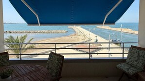 A balcony with a view of a beach, a statue, and a pier.
