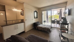 A compact room with a kitchenette, a bed, and a dining area with a view.