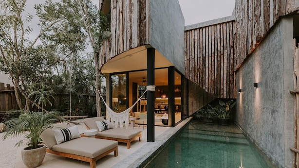 A modern outdoor pool area with a hammock, lounge chairs, and a dining area visible through a glass wall. - 3-bedroom house in amazing Tulum with Private Pool (Tulum)