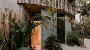 A modern building with a concrete facade, an arched entrance, and tropical plants surrounding the entrance. - 3-bedroom house in amazing Tulum with Private Pool (Tulum)