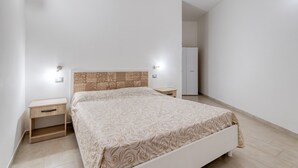 Un dormitorio con cama, mesitas de noche, armario y tocador.