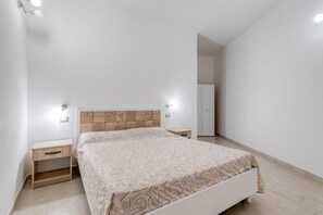 Une chambre à coucher comprenant un lit, des tables de chevet, une armoire et une petite table de nuit.