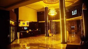 A lobby with a reception desk, a chandelier, and a marble floor. - San Antonio Blu Hotels (Awka)
