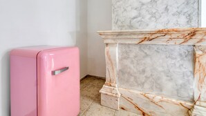 A pink refrigerator, a marble fireplace, and a tiled floor.