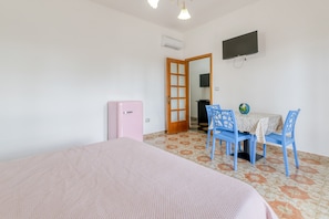 Une chambre à coucher comprenant un lit, un bureau avec des chaises, une télévision et un appareil de climatisation.