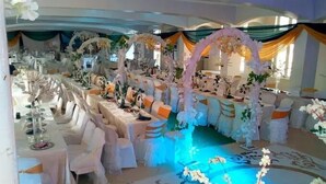 A banquet hall with long tables set for a formal event, decorated with floral arrangements and draped fabric. - Hallydays Hotel and Resort (Makurdi)