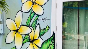 Una pared con un gran mural floral, una puerta y algunas instalaciones eléctricas.
