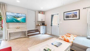 Un espacio habitable pequeño con televisor, kitchenette y cama.