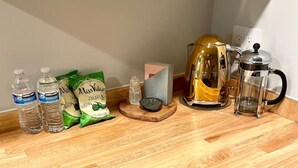 Una encimera de cocina con una cafetera, botellas de agua y cápsulas de café.
