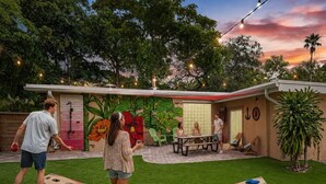 Un patio trasero con un porche, un mural y una piscina.