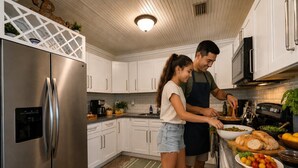 Una cocina moderna con electrodomésticos de acero inoxidable, armarios blancos y una isla central con lavamanos.