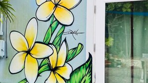 Una pared con un gran mural floral, una puerta y cableado eléctrico.