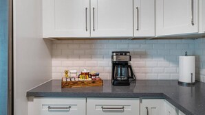 Una cocina con armarios blancos, una cafetera y un dispensador de toallas de papel.