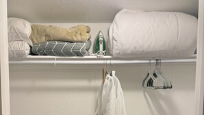 A closet with a hanging rack, a shelf with folded towels, and a robe hanging on a hook. - Mountain Greenery & Private Sauna w Stunning Pikes Peak Views (Colorado Springs)