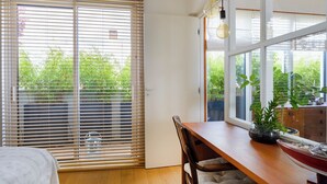 A room with a wooden dining table, a chair, a potted plant, and a view of greenery through the window. - Paris Rooftop Prestige residence (Paris)