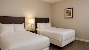 A hotel room with two beds, a nightstand with a lamp, and a framed picture on the wall. - Ramshorn Motel (Lumby)