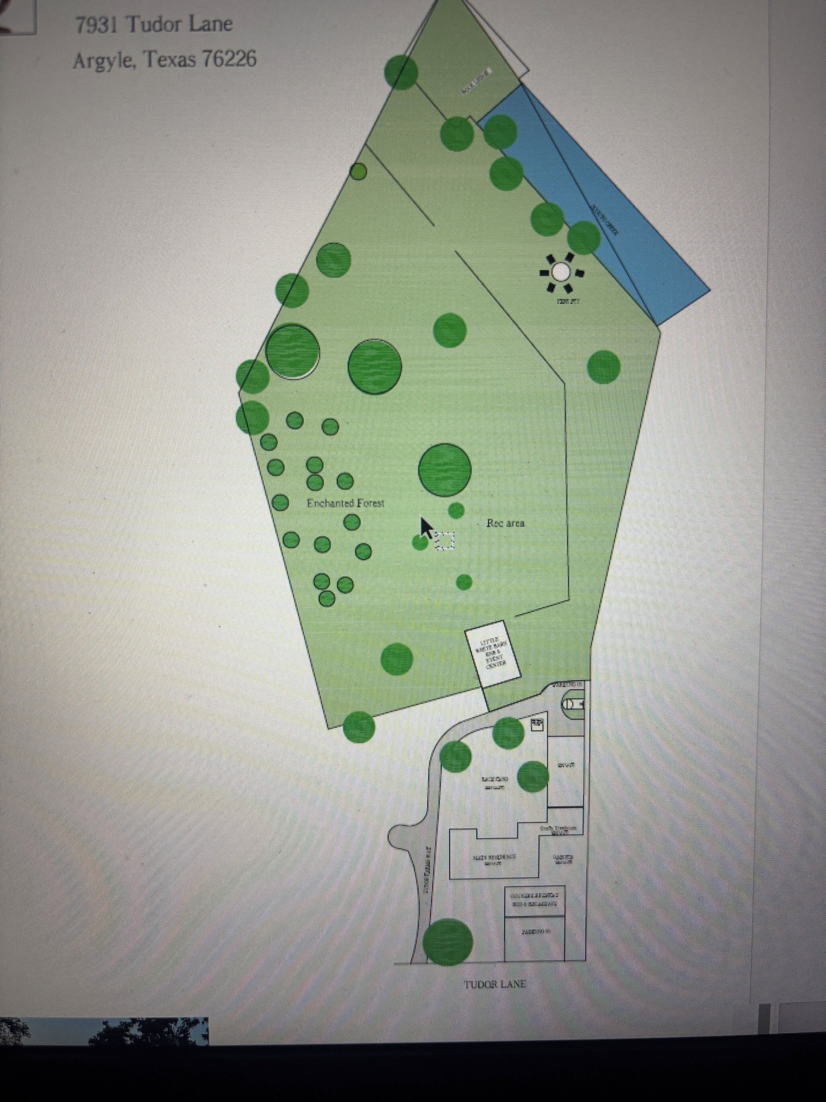 Plano de planta de una propiedad con dirección Tudor Lane, que incluye una amplia zona verde identificada como 'Enchanted Forest' y un 'Little Water & Ice Center'.
